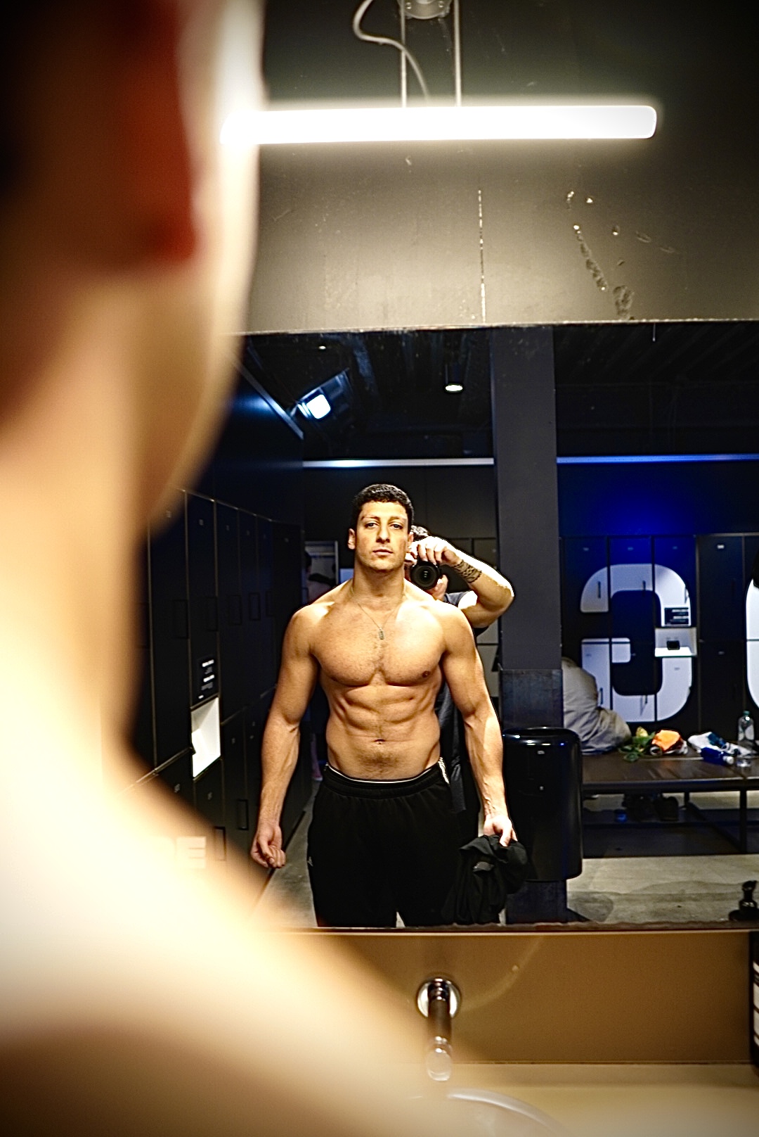 A moody, high-contrast cinematic shot of a professional athlete training in a dark, luxury private gym with dramatic lighting and deep shadows